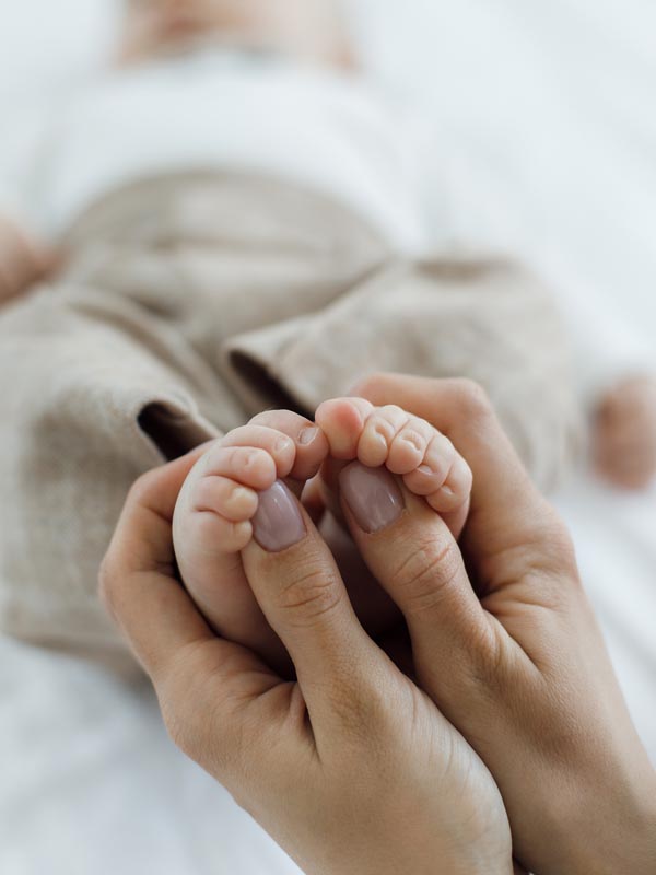 Pés de bebê recém-nascido segurados por mãos adultas